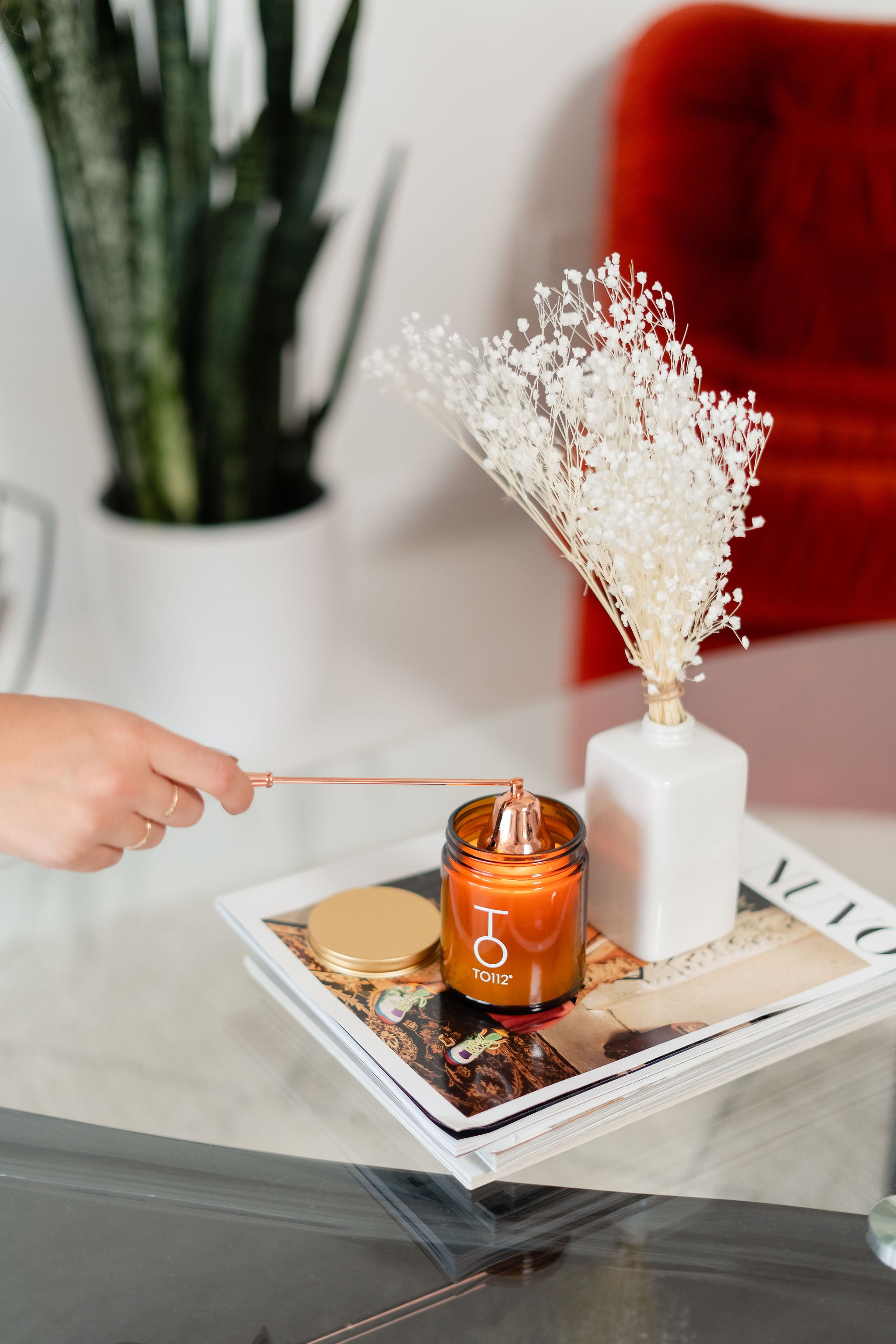 Palo Santo candle being put out with candle snuffer and vase full of baby breath flowers