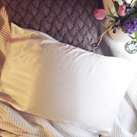 TO112 Restore silk pillowcase on bed next to pink and purple flowers in vase