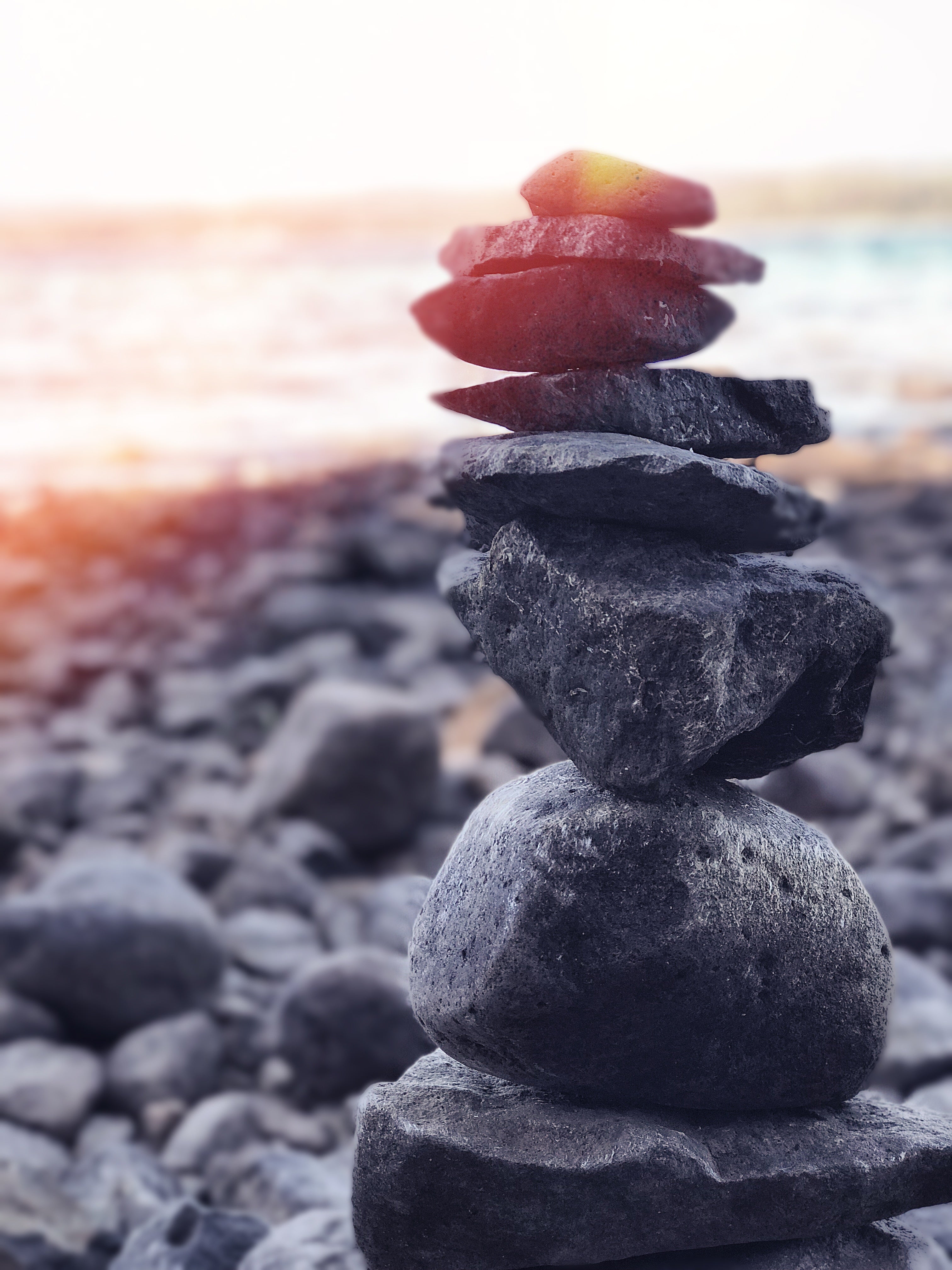 different sized and shaped rocks stacked on top of each other in front of the ocean