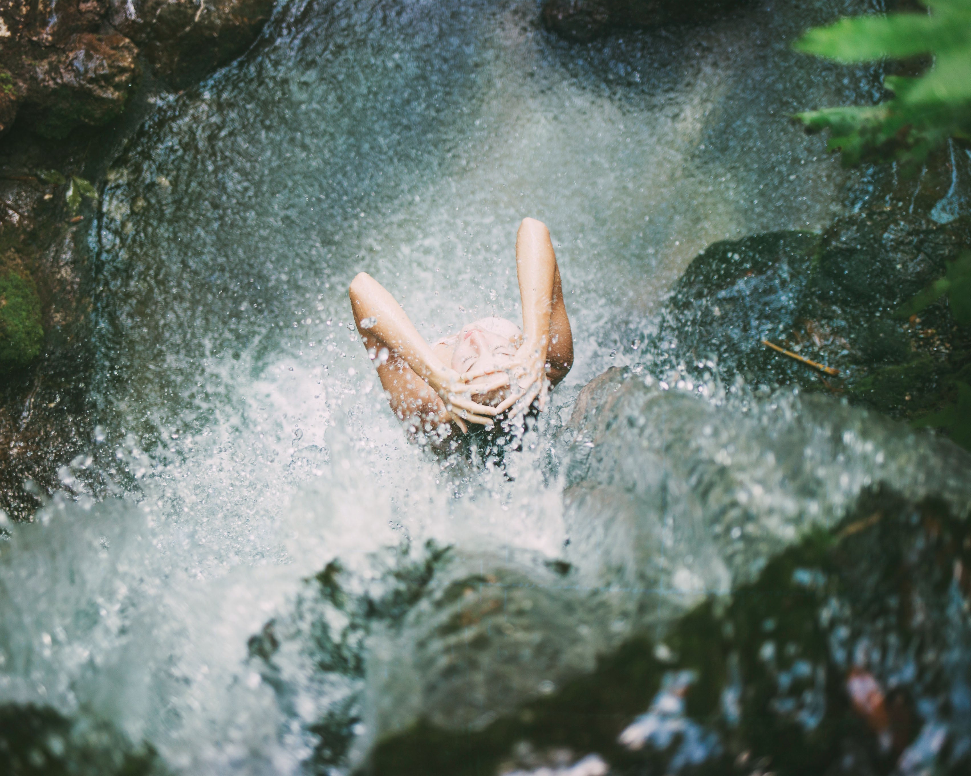 person washing hair under waterfall in tropical rain forest with TO112 products