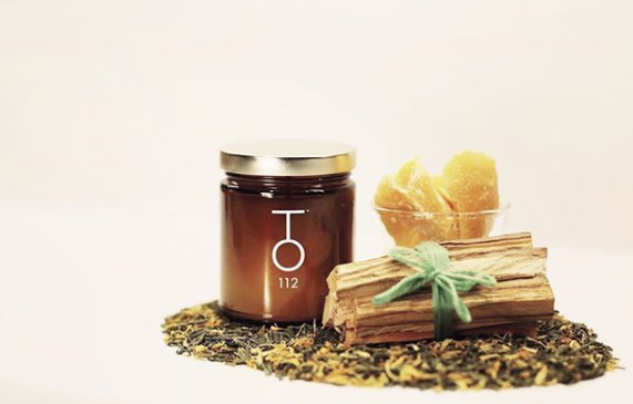 TO112 palo santo candle next to bundle of palo santo sticks