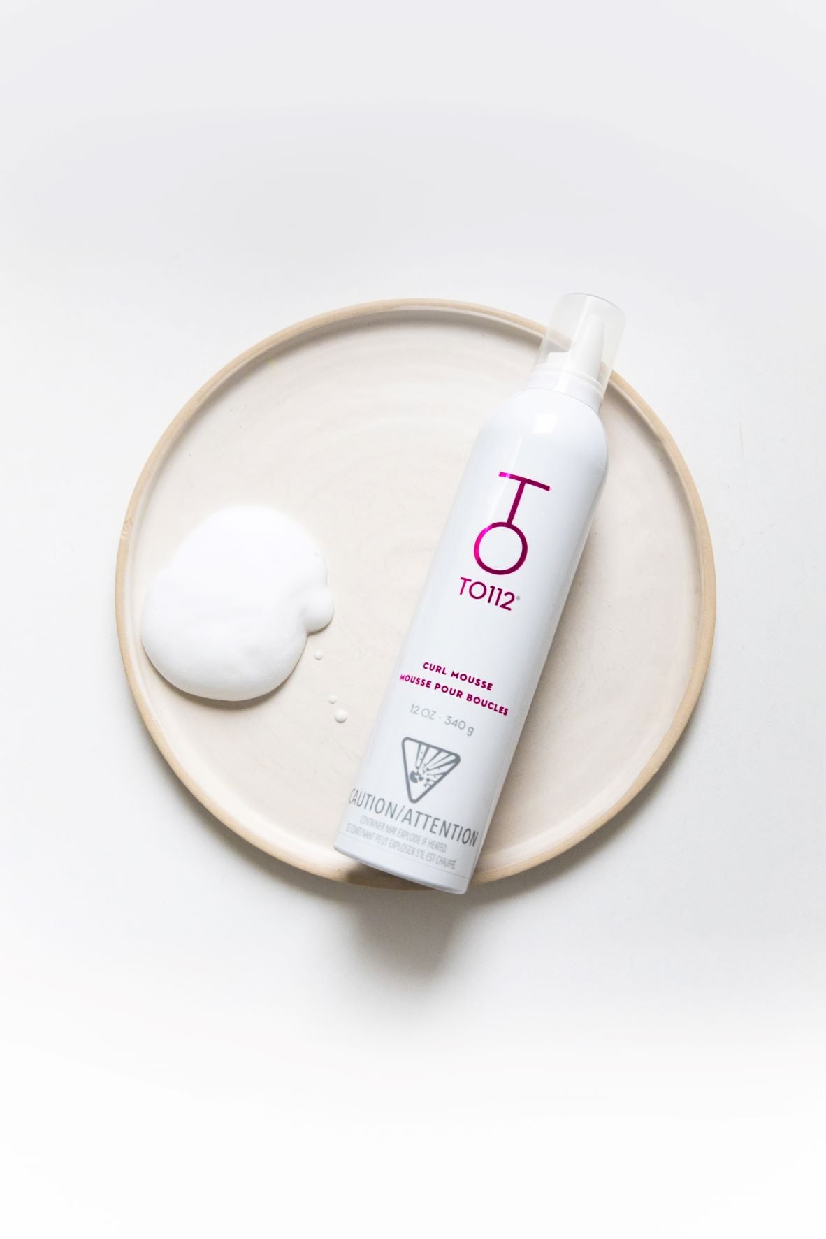 To112 Curl mousse one plate with a dollop of foam beside bottle
