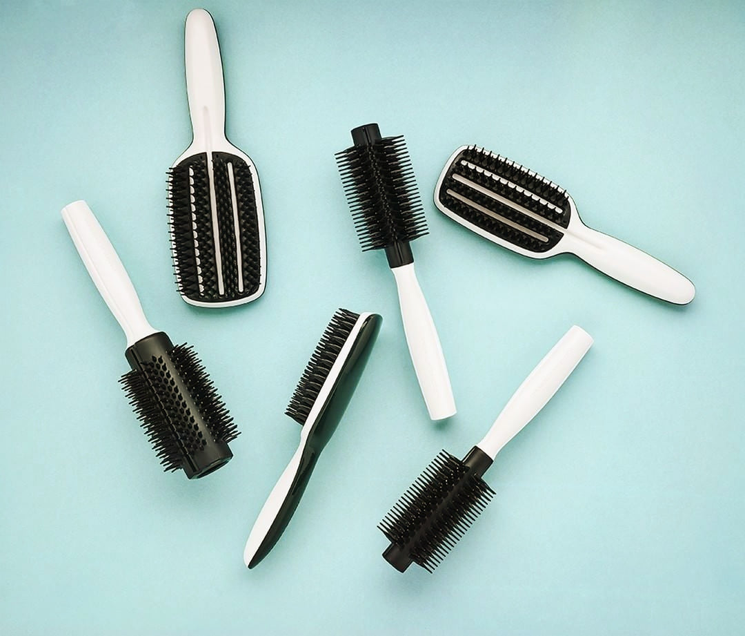 black and white hair brushes of all different kinds on blue background